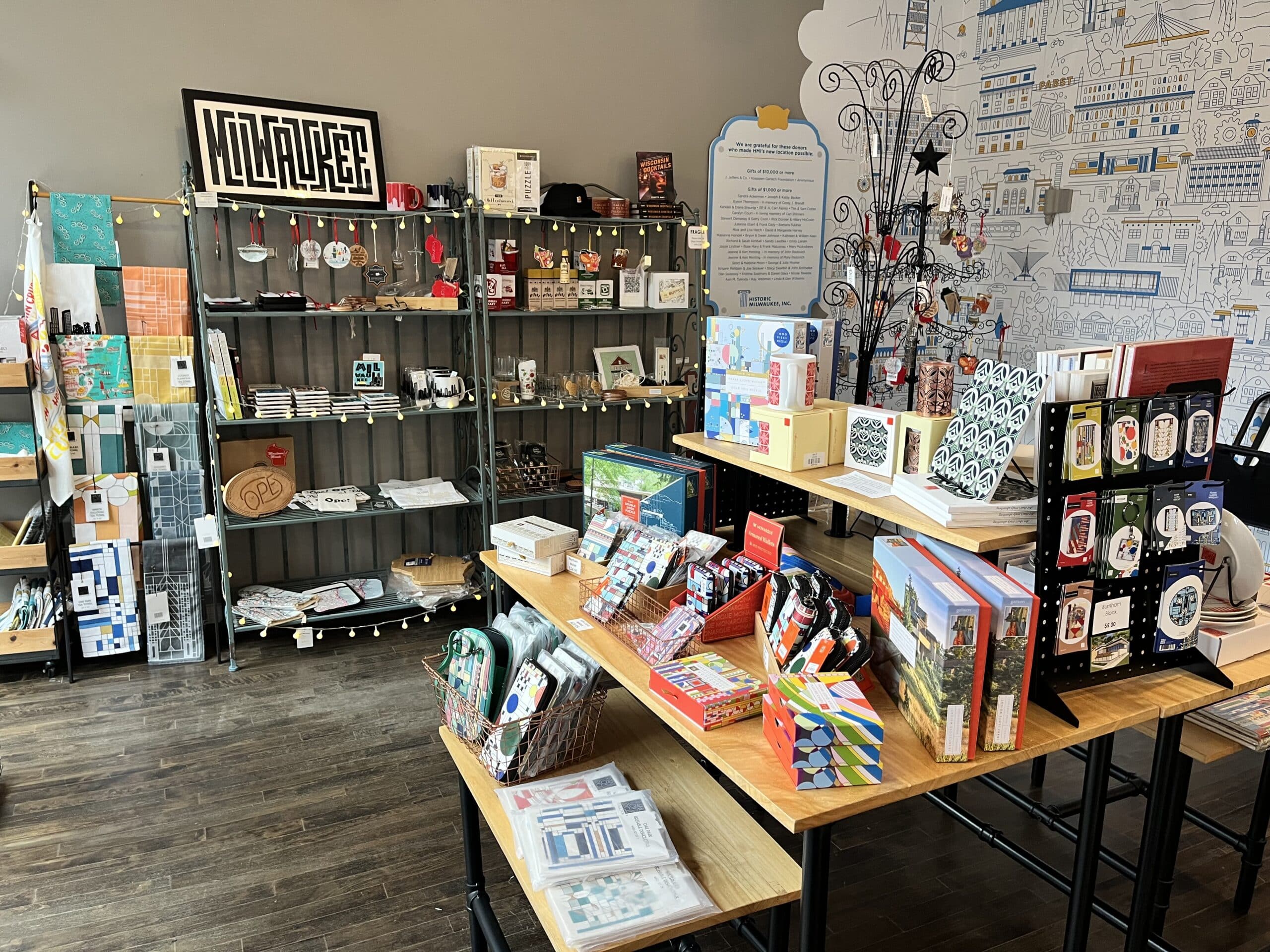A retail display featuring shelves and tables with various gift items, books, cards, and souvenirs arranged neatly in a well-lit store with wooden flooring.