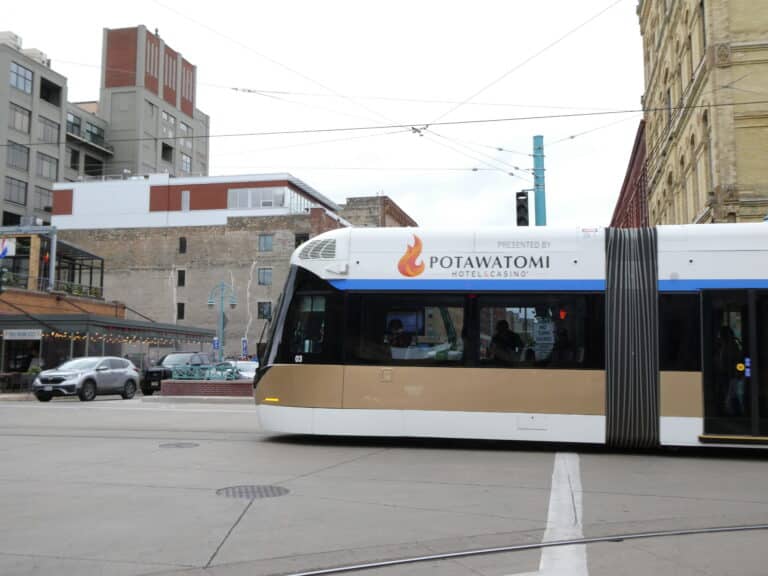 A streetcar with "Potawatomi Hotel & Casino" branding travels through an urban intersection with buildings in the background.