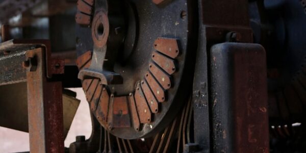 Close-up of an old, rusted industrial machine with visible coils and metal parts, set in a dimly lit environment.