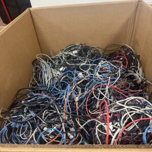 A large cardboard box filled with a tangled assortment of various colored cables and wires.