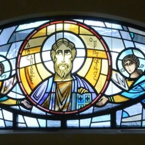 Semicircular stained glass window depicting a central haloed figure holding a book, flanked by two winged angels on either side against a blue and white background.