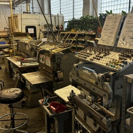 Industrial workshop with various metalworking machines, tools, and stools arranged in a row; technical diagrams are displayed above the equipment.