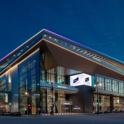 Modern glass building at night with illuminated signs reading “Baird Center”; streetlights and traffic signals are visible around the structure.