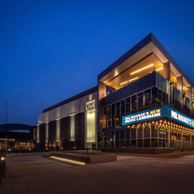 A modern concert venue at dusk with illuminated signage that reads “Milwaukee’s New Music Landmark” and “LIVE” on the building.